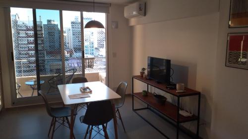 sala de estar con mesa blanca, sillas y TV en Sortie en Rosario