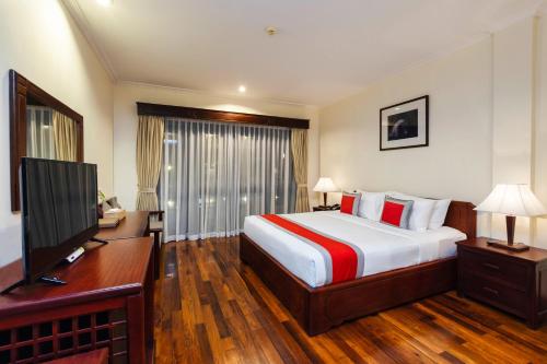 a bedroom with a bed and a desk and a television at Saem Siemreap Hotel in Siem Reap