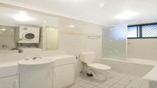 a white bathroom with a toilet and a sink at Burleigh Terraces - Hosted by Burleigh Letting in Gold Coast