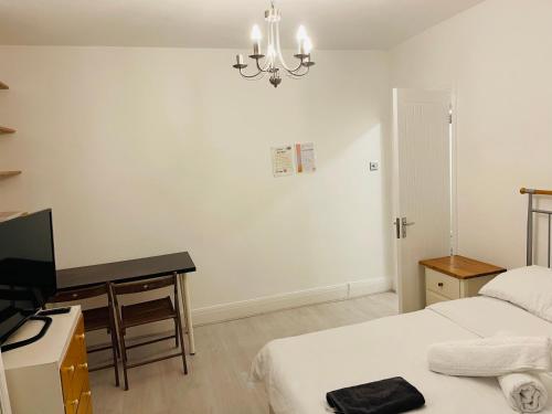 1 dormitorio con 2 camas, escritorio y TV en London Rooms with Free Parking 134, en Stone Grove