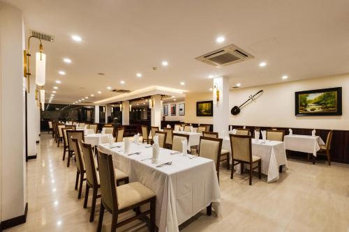 a dining room with white tables and chairs at Saem Siemreap Hotel in Siem Reap