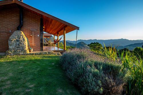 a brick building with a grassy yard next to a house at Chales Canto da Natureza in São Bento do Sapucaí