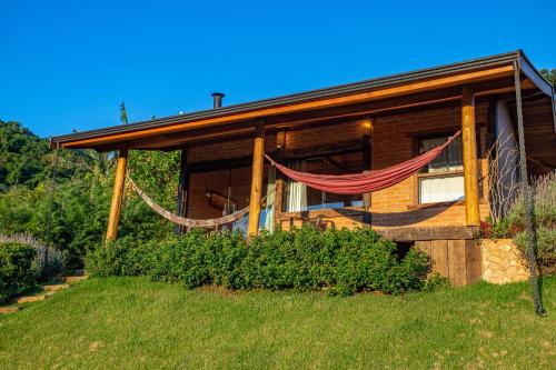 a house with a hammock in front of it at Chales Canto da Natureza in São Bento do Sapucaí