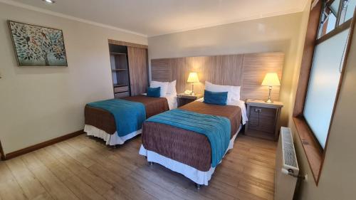 a hotel room with two beds and two lamps at Hotel D&V Concepción in Concepción
