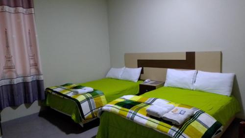 two beds in a room with green sheets at Hotel La Suite de Angelique Huacho in Huacho