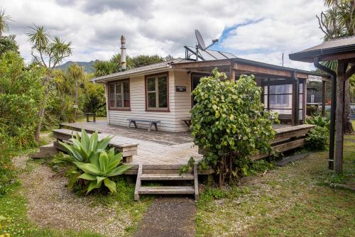a small house with a porch and a wooden deck at Solscape in Raglan
