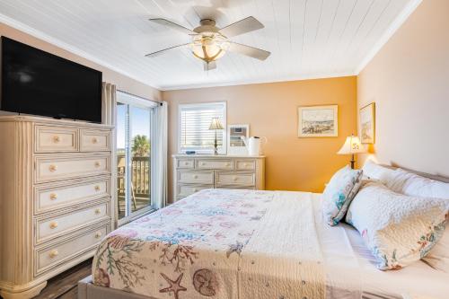 a bedroom with a bed and a dresser with a flat screen tv at Sand Dollar Villas 109 in Fernandina Beach