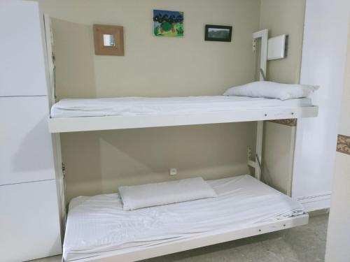 two bunk beds in a room with white sheets at SOLEA 17 in Rota