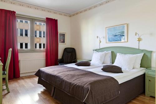 a bedroom with a large bed with red curtains at Best Western Rådmannen in Alvesta