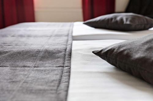 two beds with black and white sheets and pillows at Best Western Rådmannen in Alvesta