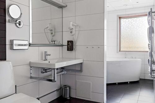 a bathroom with a sink and a tub and a mirror at Best Western Rådmannen in Alvesta