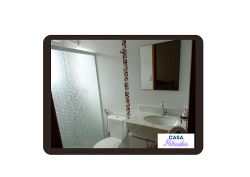 een badkamer met een toilet, een wastafel en een spiegel bij Casa Peruibe. in Peruíbe