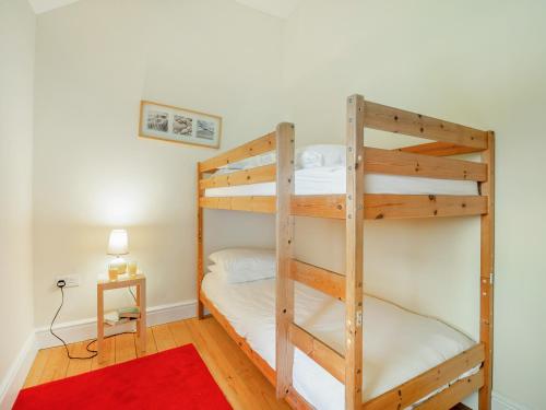 1 dormitorio con 2 literas y alfombra roja en Bwythyn-y-Saer en Abersoch