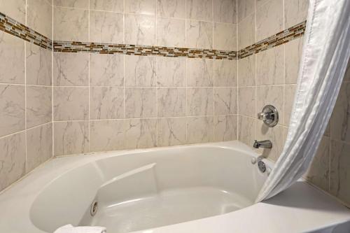 a white bath tub in a tiled bathroom at Best Western Edinburgh/Columbus in Edinburgh