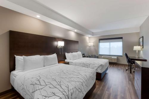 a hotel room with two beds and a desk at Best Western Premier Northwood Hotel in Timmins