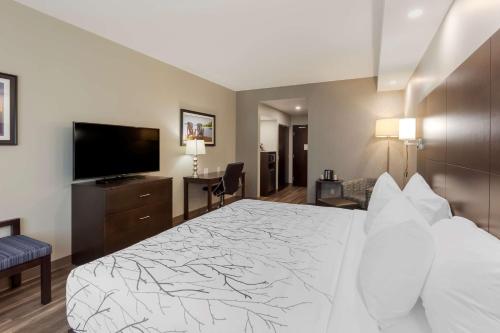 a hotel room with a bed and a flat screen tv at Best Western Premier Northwood Hotel in Timmins
