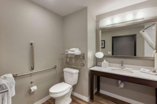 a bathroom with a toilet and a sink and a mirror at Best Western Premier Northwood Hotel in Timmins