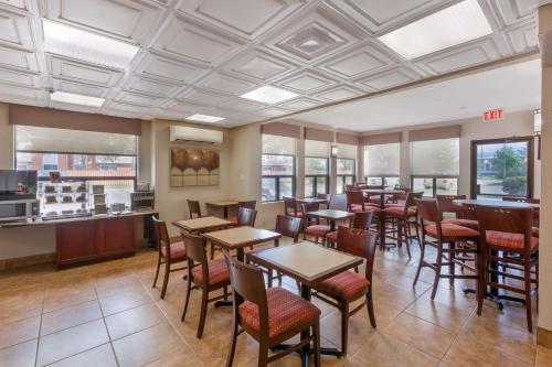 a dining room with tables and chairs and windows at Best Western Plus Rose City Suites in Welland