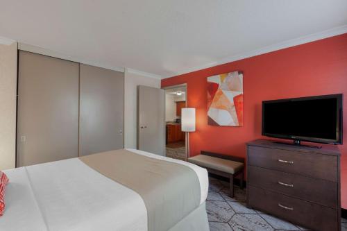 a bedroom with a bed and a flat screen tv at Best Western Plus Rose City Suites in Welland