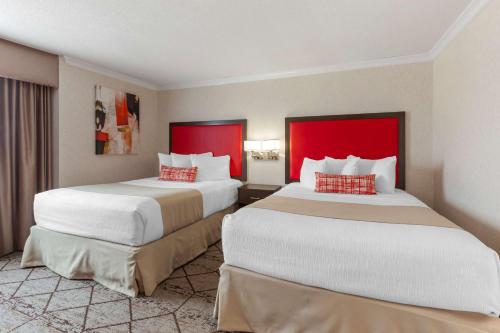 two beds in a hotel room with red accents at Best Western Plus Rose City Suites in Welland