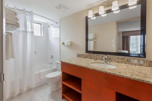 a bathroom with a sink and a toilet and a mirror at Best Western Plus Rose City Suites in Welland