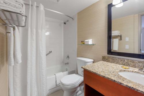 a bathroom with a white toilet and a sink at Best Western Plus Rose City Suites in Welland