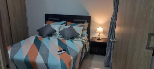 een slaapkamer met een bed met kussens en een lamp bij Moderno amplio y acogedor apartamento en el sur de cali in Cali