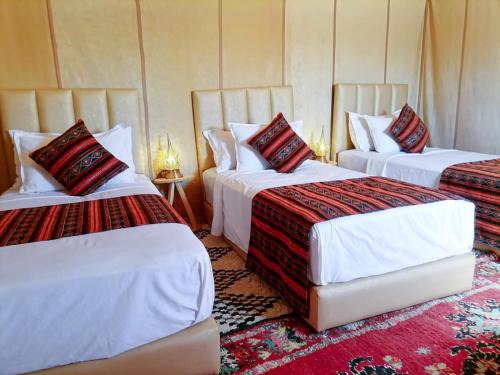 a hotel room with two beds with red pillows at Sunset Camp Merzouga in Merzouga