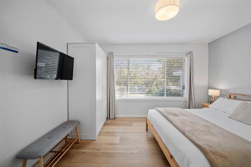a white bedroom with a large bed and a window at Elements of Hyams in Hyams Beach