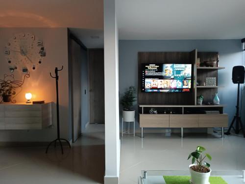 a living room with a flat screen tv on a cabinet at Apartamento con vistas a la ciudad (Penthouse) cerca al Estadio, al Boulevard de la 70 y la Avenida 80 (Casinos, restaurantes, malls y otros). in Medellín