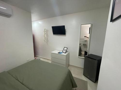 um pequeno quarto com uma cama e um espelho em Hotel Conquistador Santo Domingo em Santo Domingo