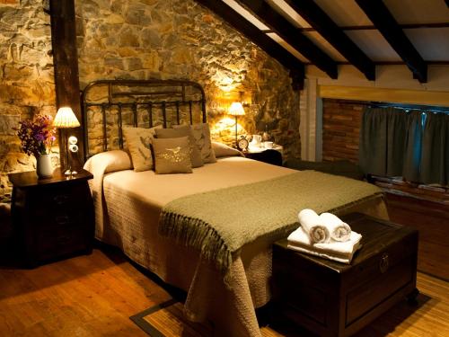 a bedroom with a bed and a stone wall at Posada Santa Ana in Suances