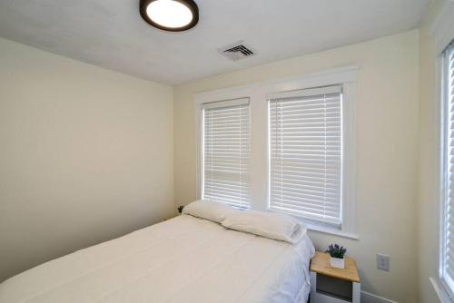 a white bedroom with a bed and two windows at Modern Three Bedroom Condo - Boston in Stoneham