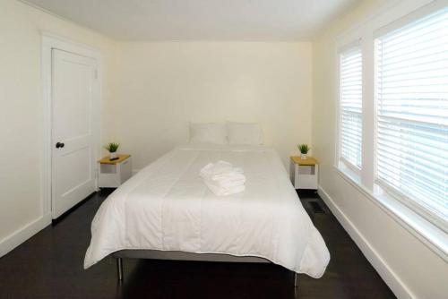 a white bedroom with a white bed and two windows at Modern Three Bedroom Condo - Boston in Stoneham