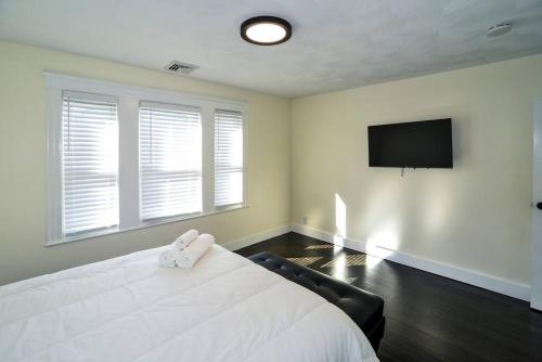 a bedroom with a white bed and a flat screen tv at Modern Three Bedroom Condo - Boston in Stoneham