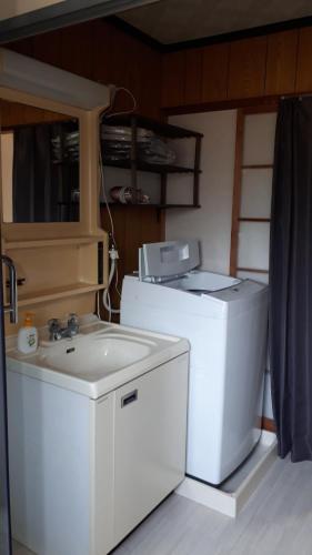 een wasmachine en een wastafel in de kamer bij ゲストハウスのスタジオ５１ in Sasebo