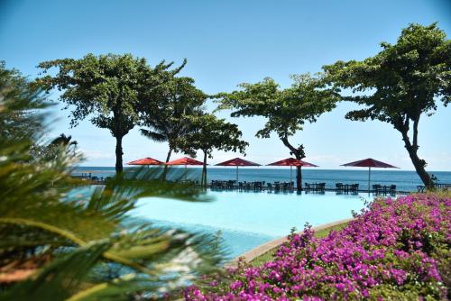 a swimming pool with umbrellas and the ocean at Le Tahiti by Pearl Resorts in Papeete