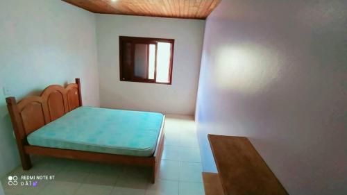 Habitación pequeña con cama y ventana en Residencial família Milani 30 metros do mar Torres, en Torres