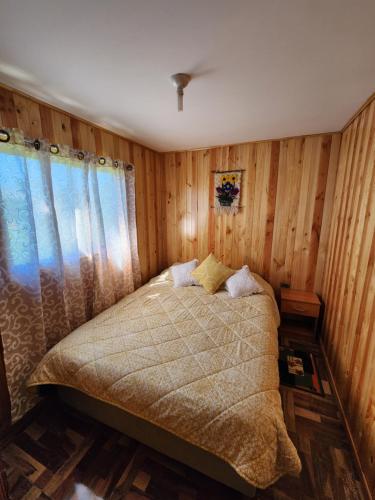 a bedroom with a bed with wooden walls and a window at Cabaña Nuevo Amanecer in San José de la Mariquina