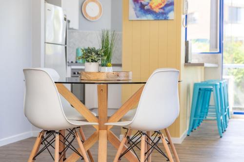 a dining room with a table and two white chairs at Heritage 103 in Tuncurry