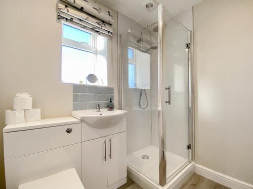 a white bathroom with a sink and a shower at The Home Stables in Southwick