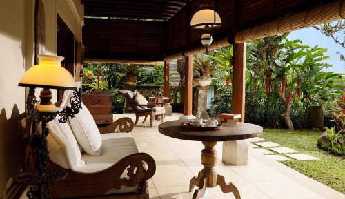a patio with a table and a chair and a lamp at Villa Inka Ubud by Nakula in Ubud