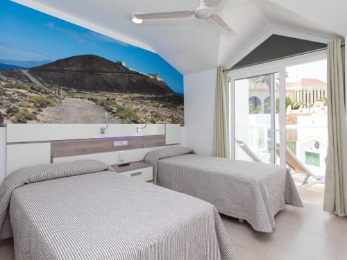 two beds in a room with a mountain view at Resort, Corralejo in Corralejo