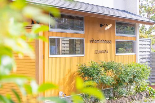 a house with a sign on the side of it at ビタミンハウス伊豆高原 - vitaminhouse IZUKOGEN in Ito