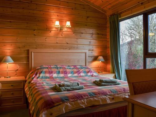 a bedroom with a bed in a log cabin at Jasmine Lodge in Woolfardisworthy