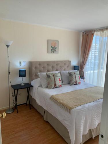 Un dormitorio con una cama blanca con almohadas y una ventana en CentriK Location Apartments Encomenderos 200, en Santiago