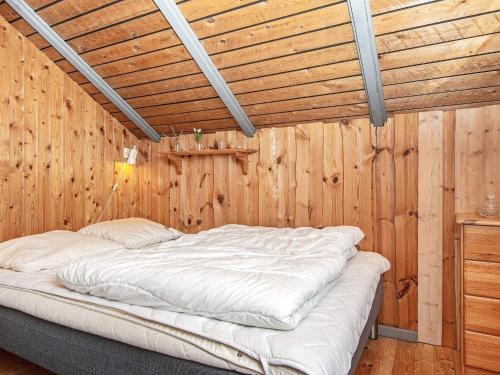 een bed in een kamer met een houten muur bij Holiday Home Mågevej VIII in Fårvang