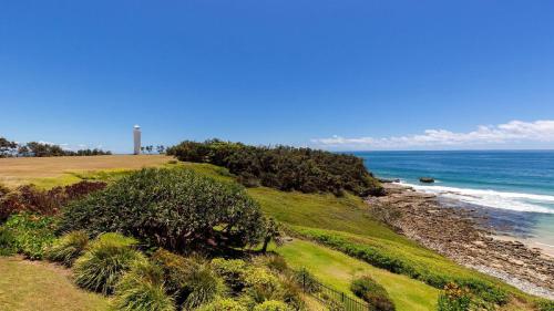 a view of a beach with the ocean and a lighthouse at Lonerock Unit 2 in Yamba
