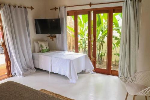 a living room with a white table and a television at Suites Taipe in Trancoso