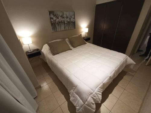 1 dormitorio con 1 cama blanca grande y 2 lámparas en Departamento en Córdoba, Villa Belgrano en Córdoba